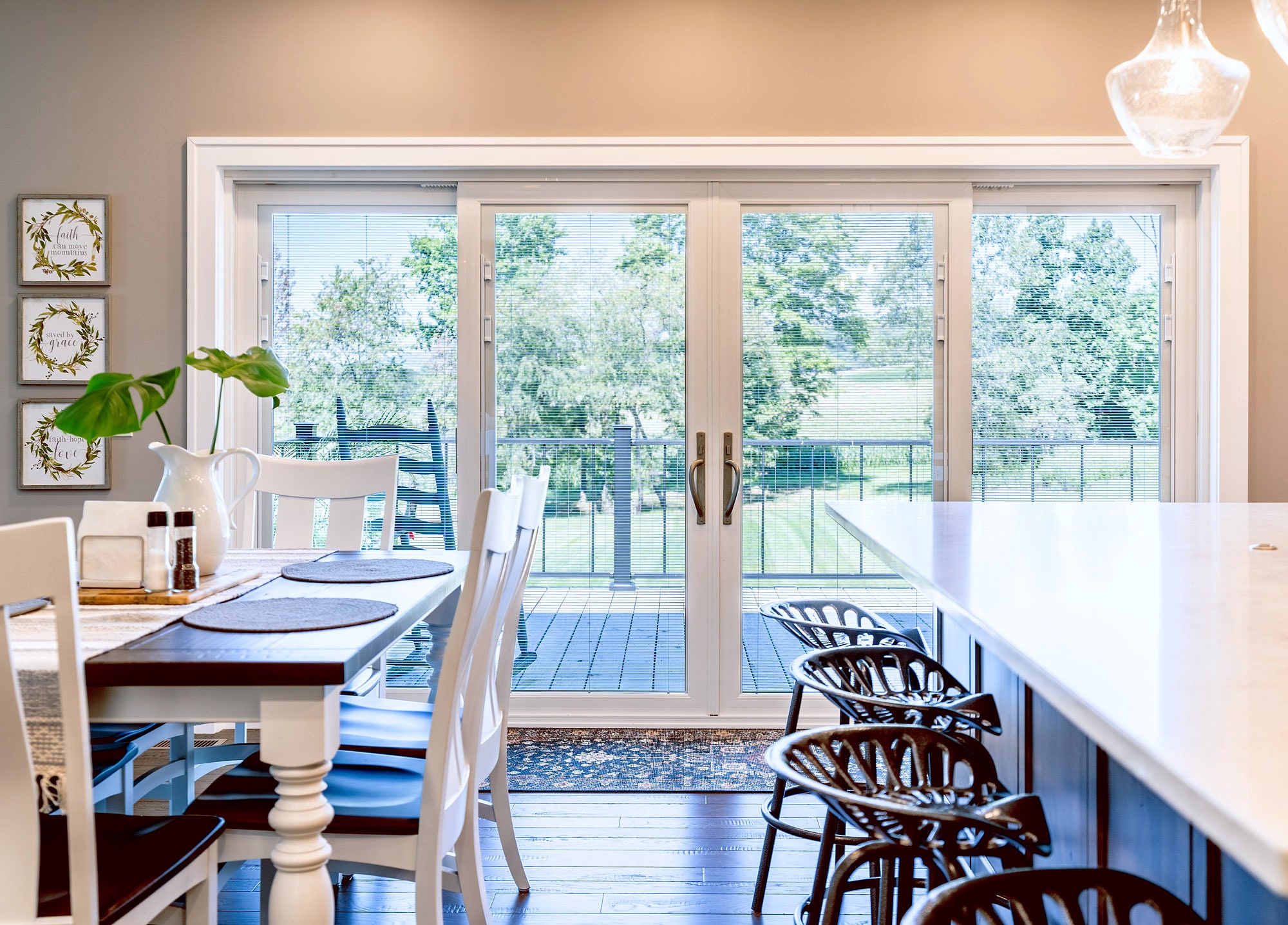 White patio door with blinds seen from dining area and kitchen island