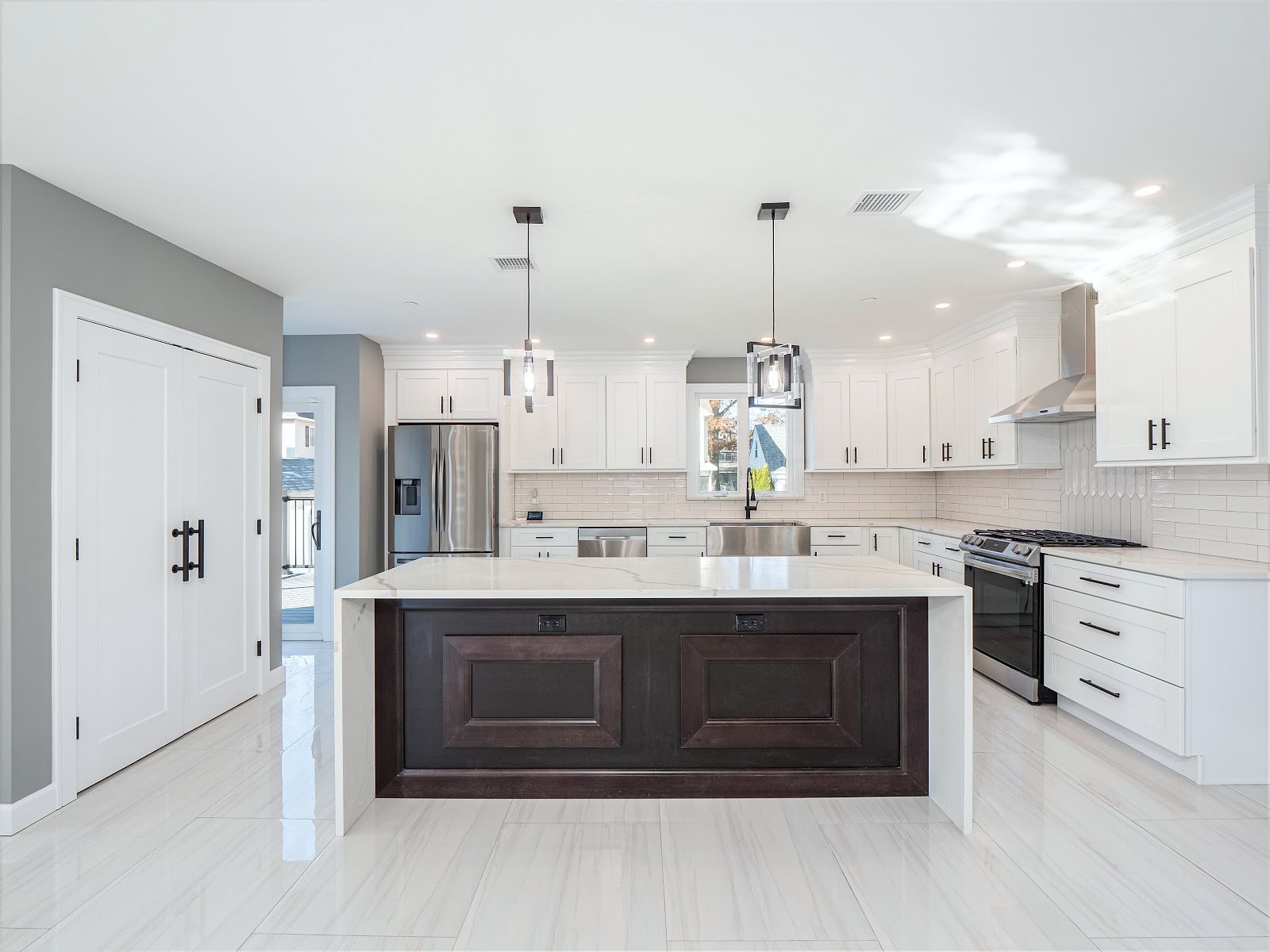 Renovated white kitchen with large island, quartz counters and pendant lights